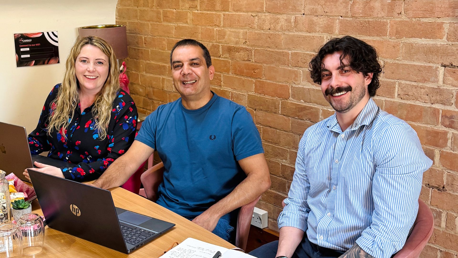 : Emma and Eddy sitting at a meeting table with client Sacha Quinney.