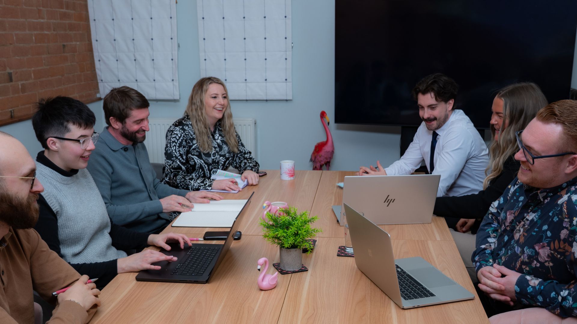 The Flamingo team having a meeting around a large table in their meeting room.