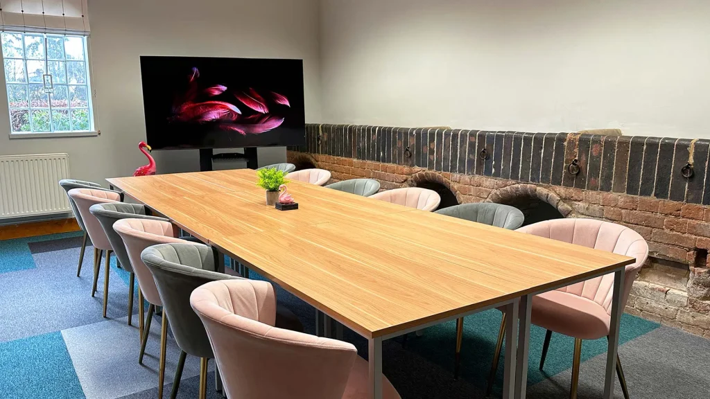 Flamingo's meeting room with a large boardroom style table and chairs, facing a large TV