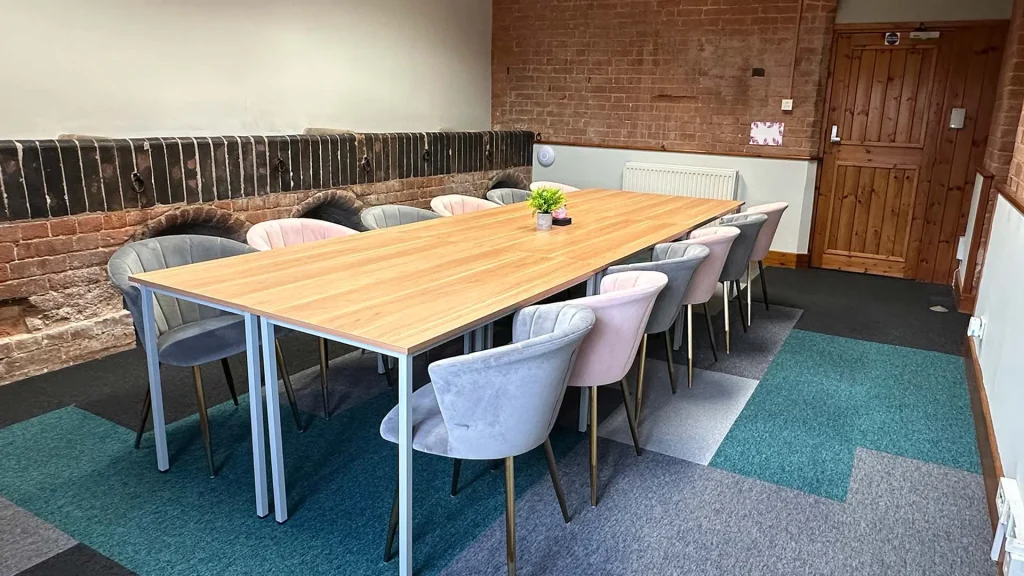 Flamingo's meeting room with a large boardroom style table and chairs, facing a large TV