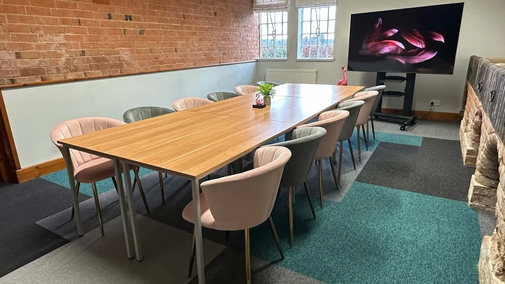 Flamingo's meeting room with a large boardroom style table and chairs, facing a large TV